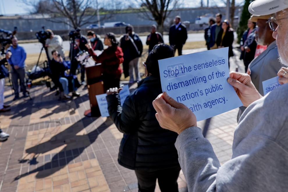 Un grupo de manifestantes sostienen pancartas tras la congresista demócrata Nikema Williams, en una protesta contra los recortes de Trump en Atlanta, Georgia.